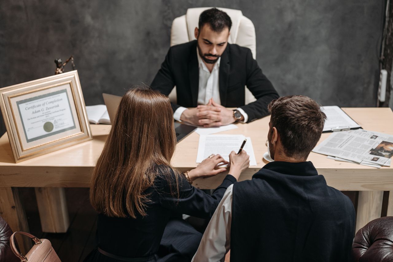about-02 A lawyer discusses legal documents with clients in an office setting.
