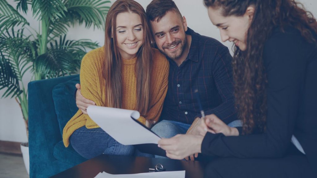 Mastering the First Impression: Your intriguing post title goes here Happy couple discussing finance with advisor in cozy office setting.